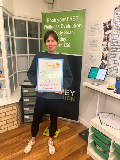 At the club, a smiling member shows the results written on her board